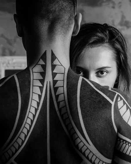 Bold black geometric work across a man's back and up his neck.